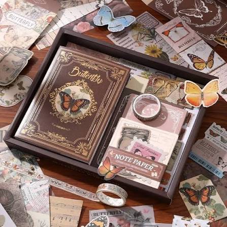 Collection of butterfly-themed stationery items including a notebook, postcards, and stickers on a wooden surface.