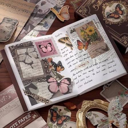 Open book with butterfly-themed decorations on a wooden surface with additional butterfly-themed items.