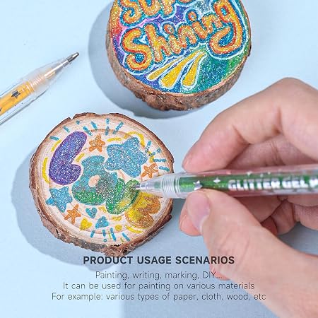 A close-up of a hand using a green marker to paint a glittery wooden slice, with two decorated wooden discs and a marker on a light blue background. Text at the bottom reads 'PRODUCT USAGE SCENARIOS' and lists painting, writing, marking, and DIY use on various materials.